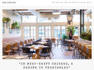 Bad Hunter Restaurant website. A screenshot of a website for a modern, casual upscale restaurant shows a brightly-lit dining room with an airy vibe, plants on the walls throughout and modern wooden tables and chairs with tasteful place settings seen throughout