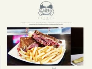 Old Towne Pub & Eatery website. A screenshot of a simple website for a suburban diner. A grey logo an emblem is seen over a large photo of a reuben sandwich with fries and a pickle
